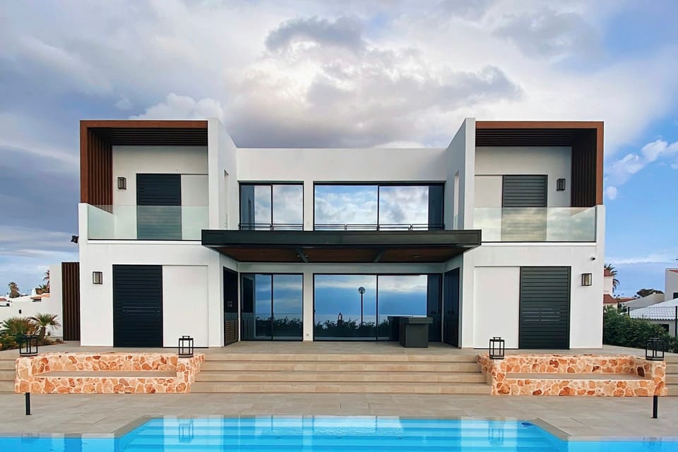 Two-storey villa with wide glass doors and balconies facing a pool