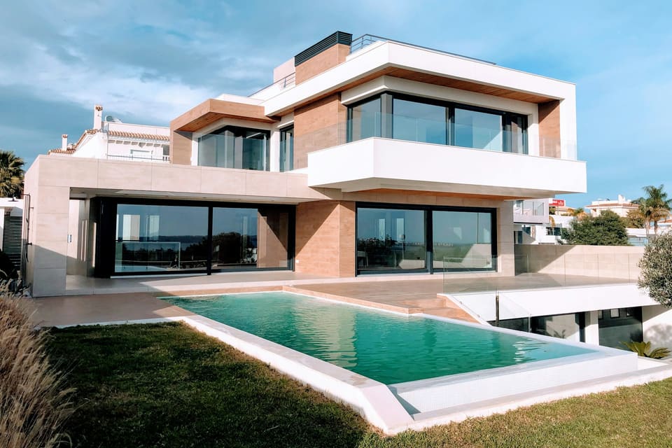 Modern villa with floor-to-ceiling sliding doors opening onto a pool
